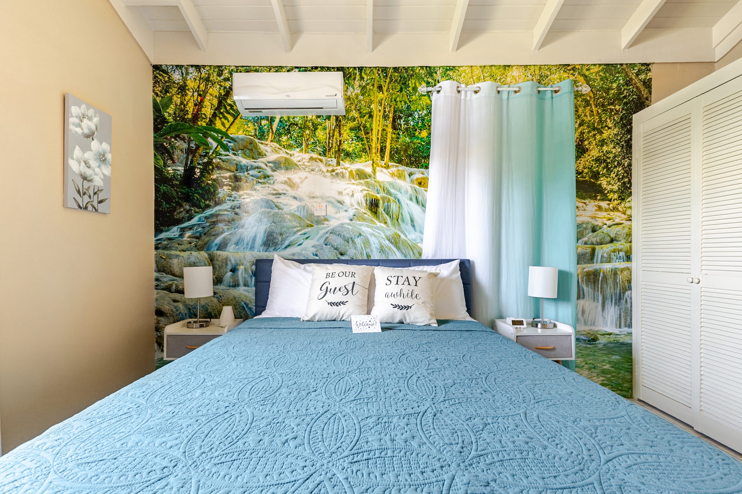 The waterfall-inspired queen bedroom at Yons Paradise, with blue bedding and a forest mural
